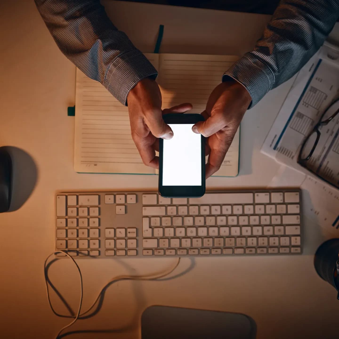 A businessman reviewing work on a mobile phone late in the office