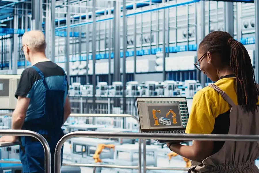 An engineer with a laptop on a factory floor beside the automated line