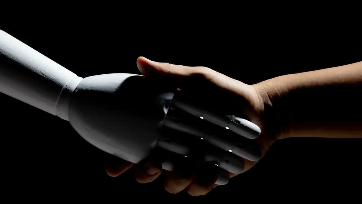 A white robot hand shaking a human hand against black