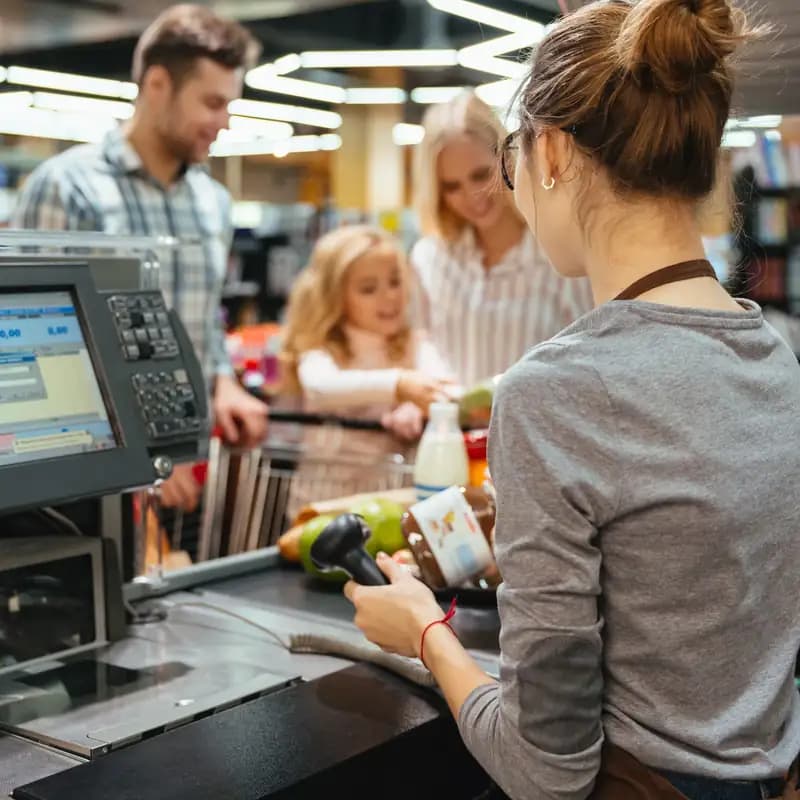A cashier serving a family at a supermarket checkout