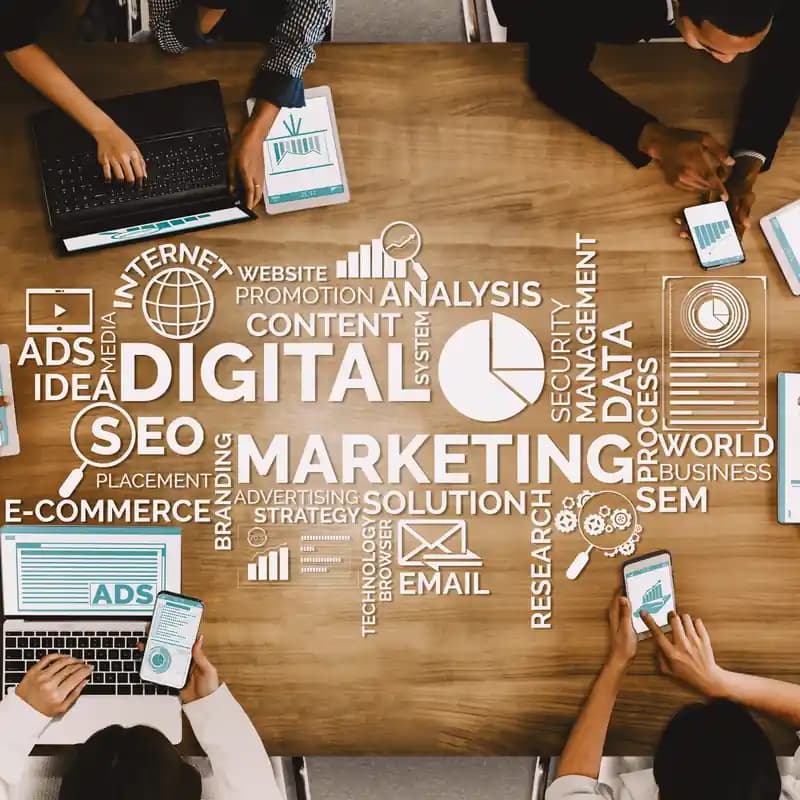 A marketing team's hands over a desk of reports, 'digital marketing' written across it