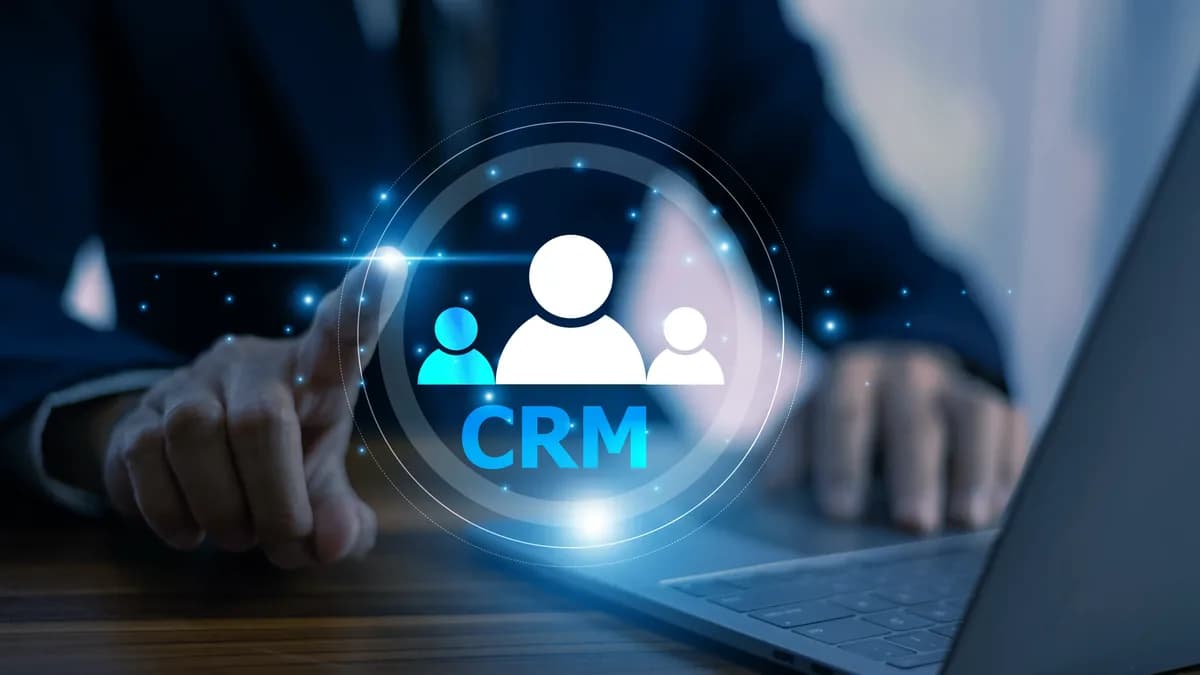 A businessman touching a glowing CRM icon over his laptop
