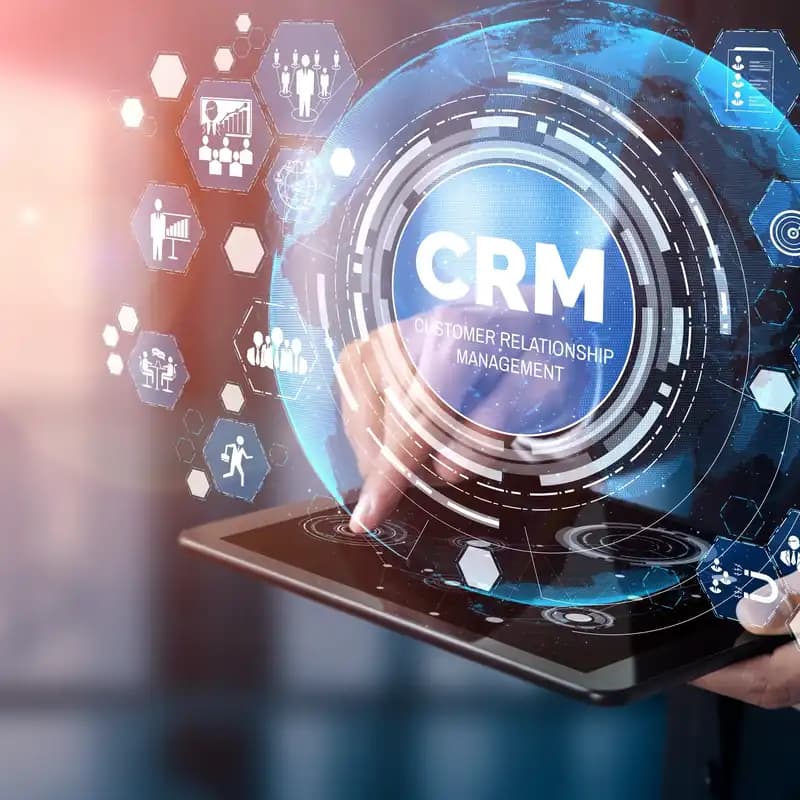 A hand touching a CRM icon on a tablet