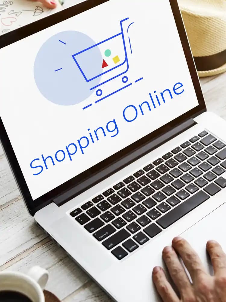 A laptop showing 'Shopping Online' beside a credit card and a straw hat