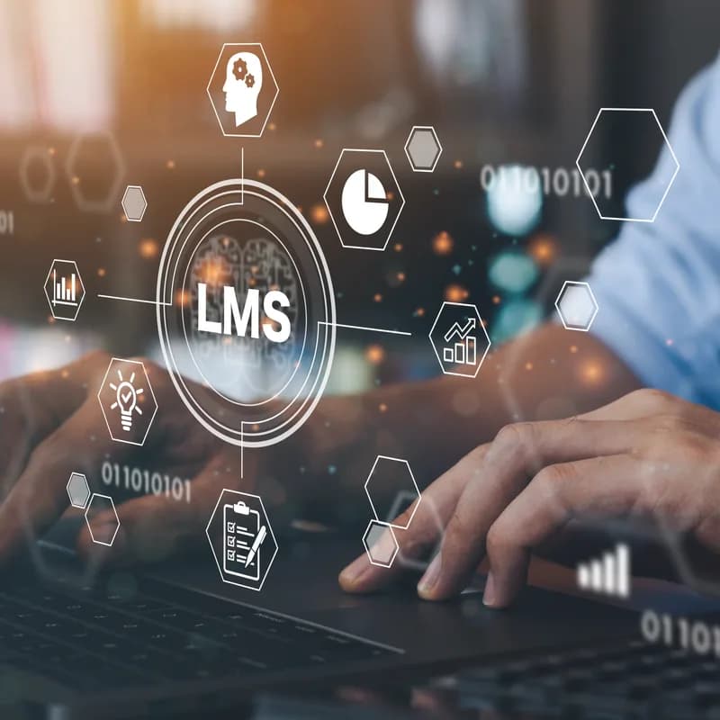 Hands at a laptop with LMS course icons above the keys