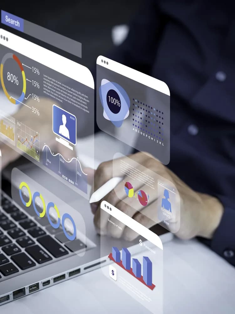 A businessman at a laptop with analytics panels rising from the keyboard