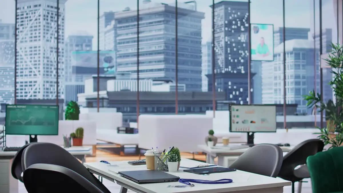 Empty modern office with desks and monitors overlooking city towers.
